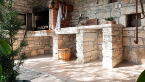 Un intérieur rustique en pierre, avec un four en briques, un tonneau en bois et un mur de pierres.