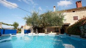 Une piscine avec un mur en pierre et un arbre en arrière-plan.
