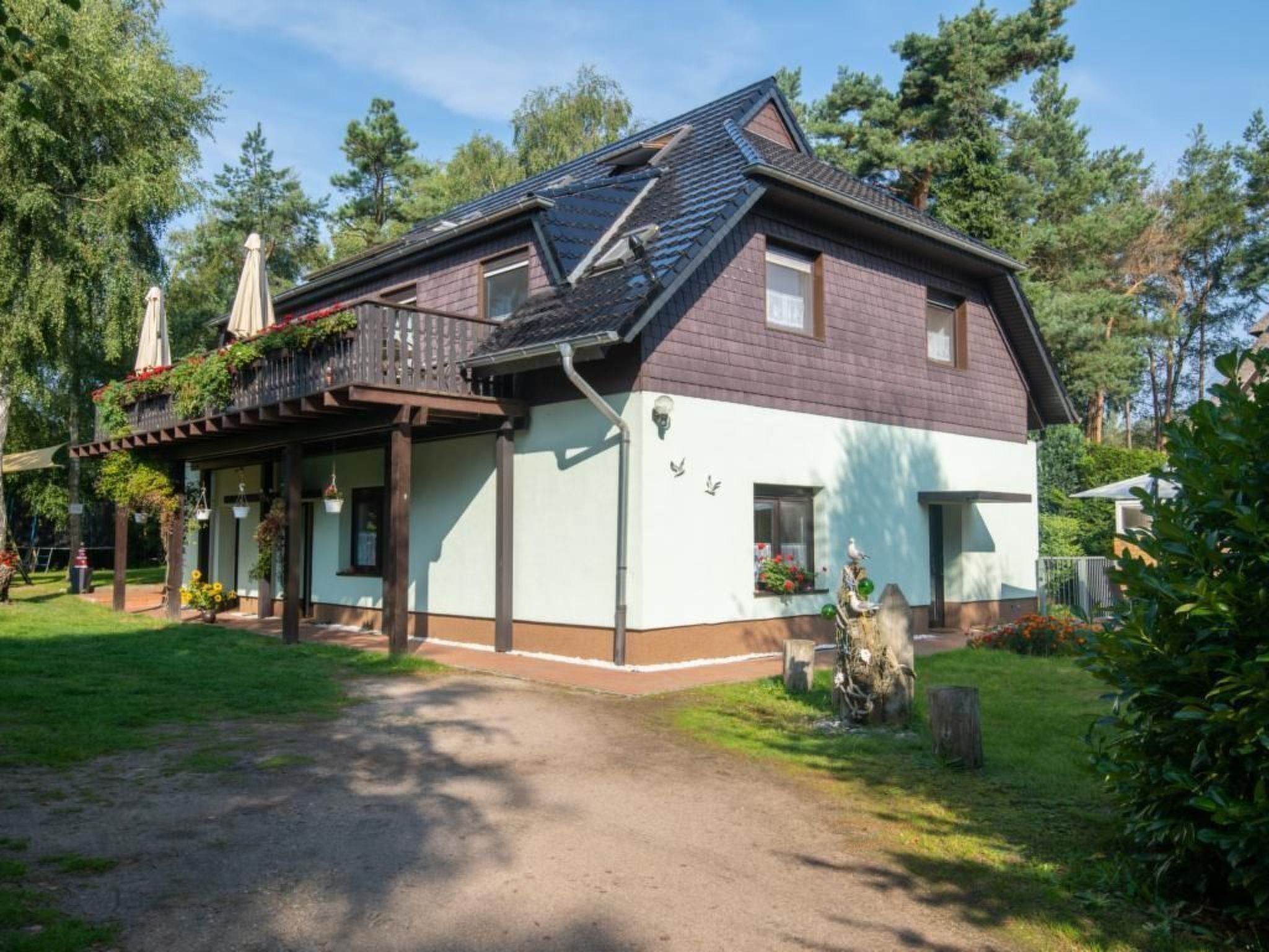 Kaksikerroksinen rakennus, jossa on parveke, katettu kuisti ja pieni puutarha-alue.