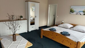 Een slaapkamer met een houten bed, een klein nachtkastje, een witte kledingkast en een spiegel.