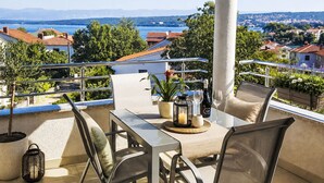 Een terras met een tafel, stoelen, een kaars en een fles wijn.
