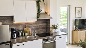 Een moderne keuken met witte kasten, een roestvrijstalen koelkast, een inbouwoven en een zwart aanrecht.