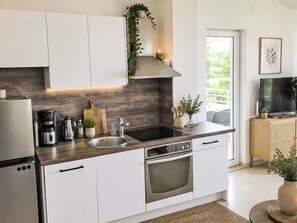 A modern kitchen with white cabinets, a stainless steel refrigerator, a built-in oven, and a black countertop. - mit Blick auf das Wasser by Interhome (Krk/Milohnići)