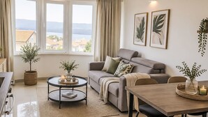 Een moderne woonkamer met een bank, een eettafel, een salontafel en uitzicht op een meer.