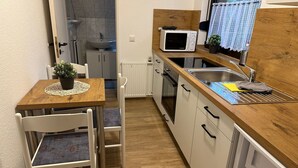 A compact kitchen with a wooden countertop, a built-in microwave, a sink, and a dining area with a table and chairs. - Wohnung 1 by Interhome (Ahrenshoop)