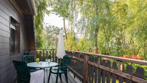 A wooden deck with a table and chairs, surrounded by a wooden fence and lush greenery. - Wohnung 1 by Interhome (Ahrenshoop)