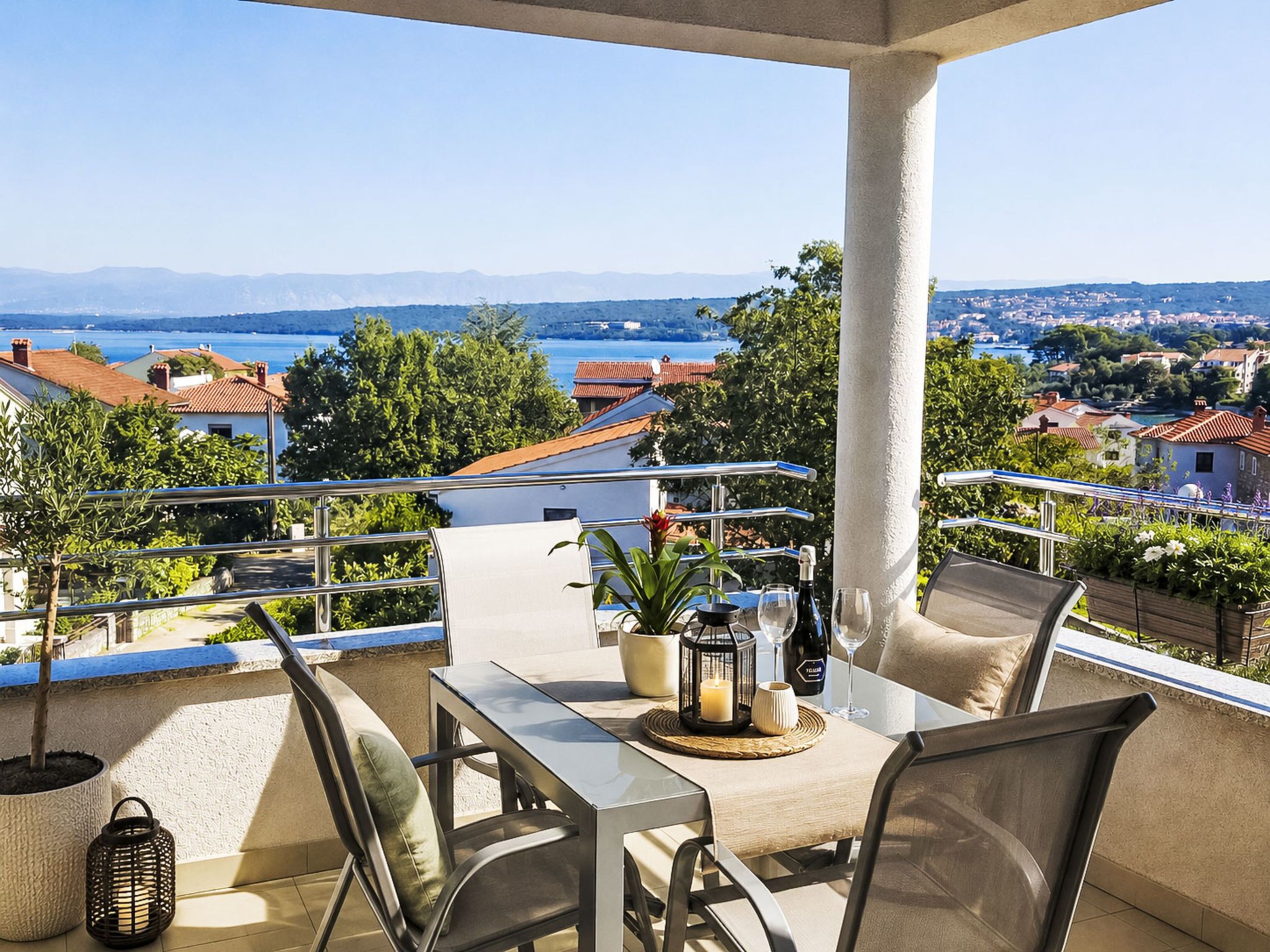 Una terrazza con tavolo, sedie, una candela e una bottiglia di vino.