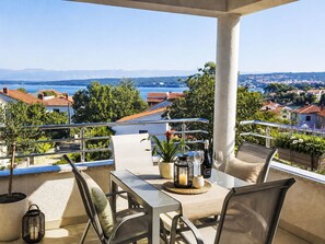 Eine Terrasse mit Tisch, Stühlen, einer Kerze und einer Weinflasche.
