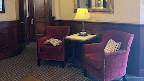 A hotel lobby with two armchairs, a small table with a lamp, a mirror, and a patterned rug. - Remodeled studio in the heart of  historic downtown Durango! (Durango)