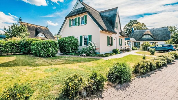 A traditional European house with a thatched roof, surrounded by well-maintained hedges and a paved driveway. - Schwanke´s Feri by Interhome (Gingst)