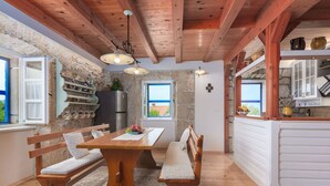 A rustic kitchen with wooden beams, a stone wall, and a view of the sea. - "VillaTonka auf der Insel Krk, Malinska" by Interhome (Krk/Milohnići)