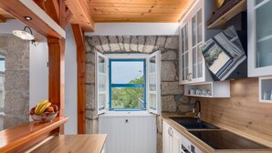 A compact kitchen with a stone wall, wooden ceiling, and a window with an open shutter. - "VillaTonka auf der Insel Krk, Malinska" by Interhome (Krk/Milohnići)