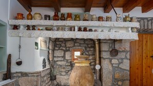 A rustic interior with a stone fireplace, wooden shelves with pottery, and a large clay pot in the center. - "VillaTonka auf der Insel Krk, Malinska" by Interhome (Krk/Milohnići)
