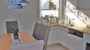 Una cocina moderna con armarios blancos, encimera de madera y una mesa de comedor con sillas.
