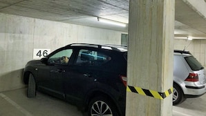 A parking garage with concrete walls, a car parked in a spot marked with the number 46, and yellow caution tape near a pillar. - Appartement in Langfurth mit Kleinem Balkon by Interhome (Langfurth)