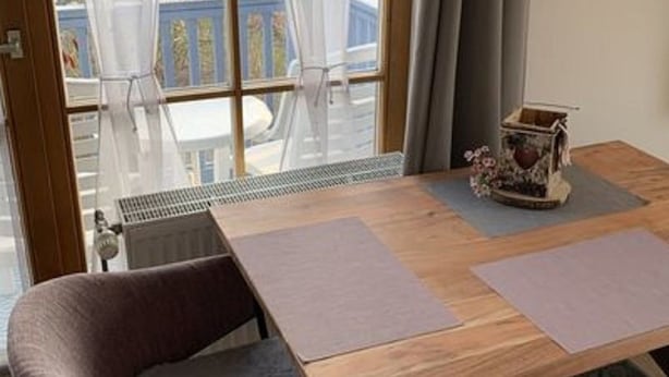 A dining area with a table, two chairs, a decorative vase, and a view of a deck and greenery outside. - Appartement in Langfurth mit Kleinem Balkon by Interhome (Langfurth)