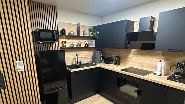 A modern kitchen with black appliances, a wooden countertop, and a black refrigerator. - Winterberg by Interhome (Winterberg)