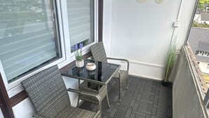 A balcony with two wicker chairs, a glass table, and a potted plant. - Winterberg by Interhome (Winterberg)