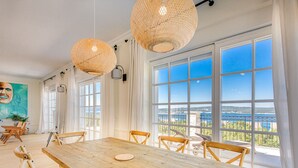 A spacious dining area with a wooden table and chairs, large windows with a view of the sea, and hanging wicker lamps. - Villa Vespera by Interhome (Crikvenica)
