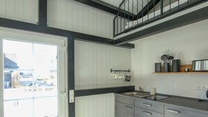 Una cocina moderna con horno integrado, un lavamanos y una encimera. Hay una ventana con vistas al exterior.