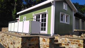 A two-story building with a green exterior and white trim, featuring a stone wall foundation and a metal fence. - mit Grill in Bad Marienberg by Interhome (Bad Marienberg)