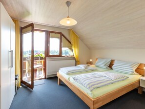 A bedroom with a wooden bed, a window with curtains, a radiator, and a view of the outdoors. - "Säntisblick" by Interhome (Hergensweiler)