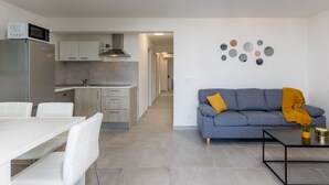 A modern kitchen with a built-in microwave, a dining area with white chairs, and a living room with a gray sofa and a coffee table. - Moderne Wohnung in Crikvenica mit schöner Terrasse by Interhome (Crikvenica)