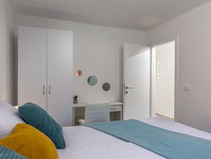 Ein Schlafzimmer mit einem Bett, einem Kleiderschrank, einem Schreibtisch und einer Tür.