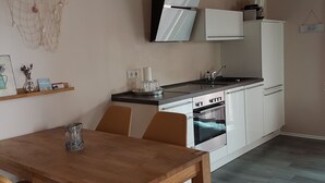 Ett kompakt kök med vita skåp, en inbyggd ugn och en svart bänkskiva.