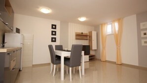 Una cucina moderna con zona pranzo, che include un tavolo bianco, sedie grigie e una televisione.