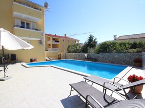 Ein Swimmingpool mit Liegestühlen und einem weißen Sonnenschirm.