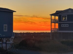 A coastal building with a balcony overlooking the beach at sunset. - Family Tides~Steps to Sand~Pool!~Fun for All! (Oak Island)
