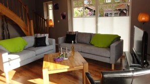 Ein Wohnzimmer mit zwei grauen Sofas, einem Holztisch und einem Fernseher.