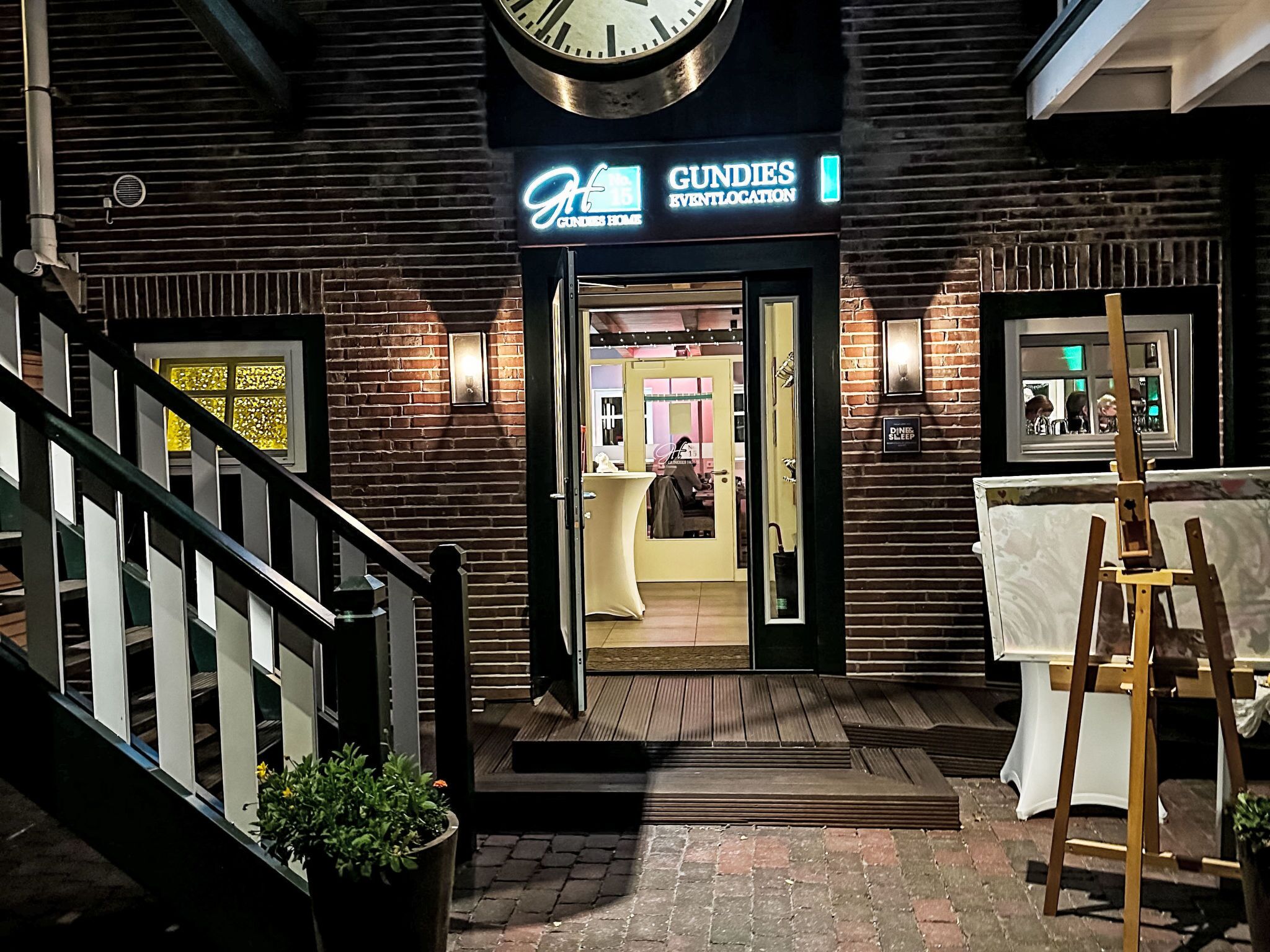 A hotel entrance with a sign for 'GUNDES EVENTLOCATION' and a staircase leading up to the entrance.