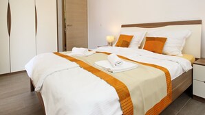 A hotel room with a large bed, two pillows, a nightstand, and a wooden door. - Tolle Ferienwohnung in Baška mit Eigener Terrasse by Interhome (Krk/Baška)