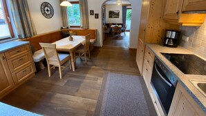 Cocina compacta con armarios de madera, una zona de comedor con banco y vistas al comedor.