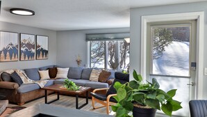 Una sala moderna con un sofá modular, una mesa de centro y una planta en maceta.