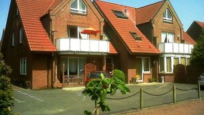 A red-brick building with a sloped roof, a gated entrance, and a small car parked in front. - Helle Erdgeschosswohnung mit sonniger Terrasse by Interhome (Altfunnixsiel)