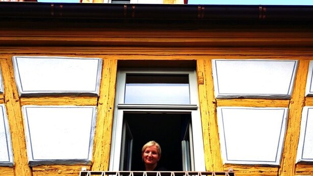 Un immeuble doté d’un balcon avec une rambarde en métal et d’une fenêtre à cadre blanc.