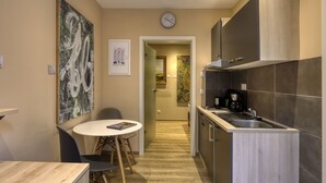 Une cuisine moderne équipée d’une cuisinière intégrée, d’un évier et d’un réfrigérateur. On y trouve une table à manger avec des chaises, ainsi qu’un tableau accroché au mur.