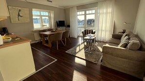 A modern living room with a wooden dining table, a sofa, and a TV. - in Wenningstedt-Braderup (Sylt) by Interhome (Wenningstedt-Braderup)