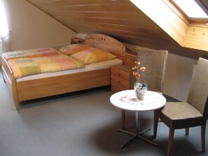 A small, cozy bedroom with a single bed, a nightstand, a chair, and a small table with a vase of flowers. - in der Vulkaneifel by Interhome (Ulmen)