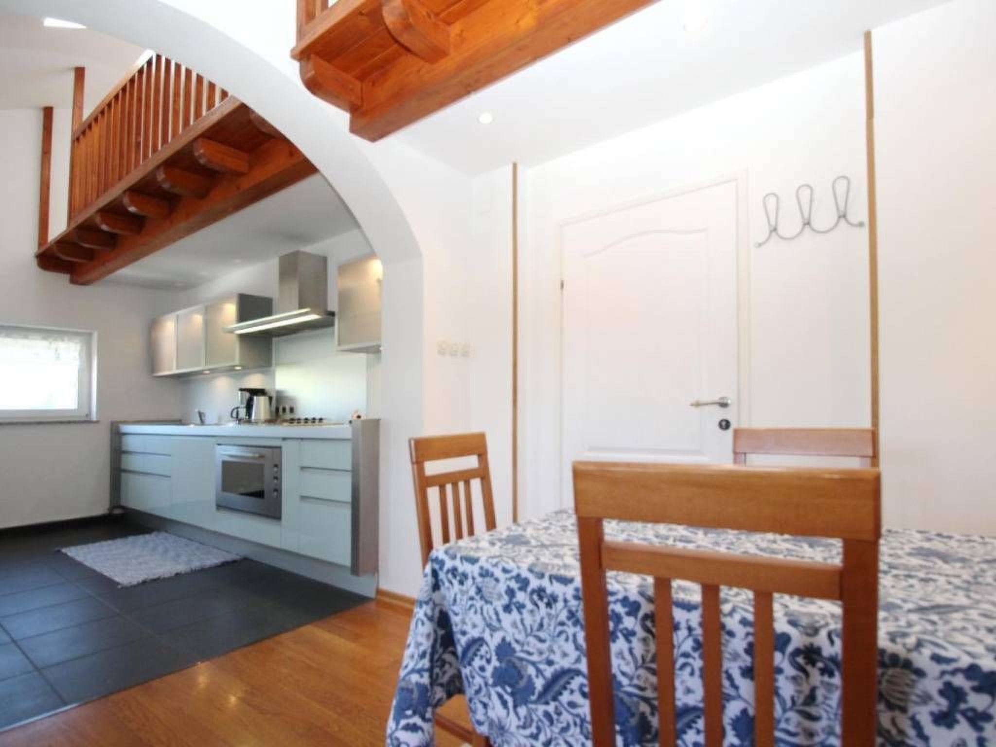 Een compacte keuken met moderne apparatuur, een eethoek met een houten tafel en stoelen, en een trap naar een hoger gelegen verdieping.