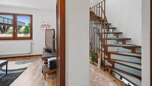 A modern interior with a wooden staircase, a flat-screen TV, and a view of the outdoors. - Haus-Fernblick by Interhome (Mechernich)