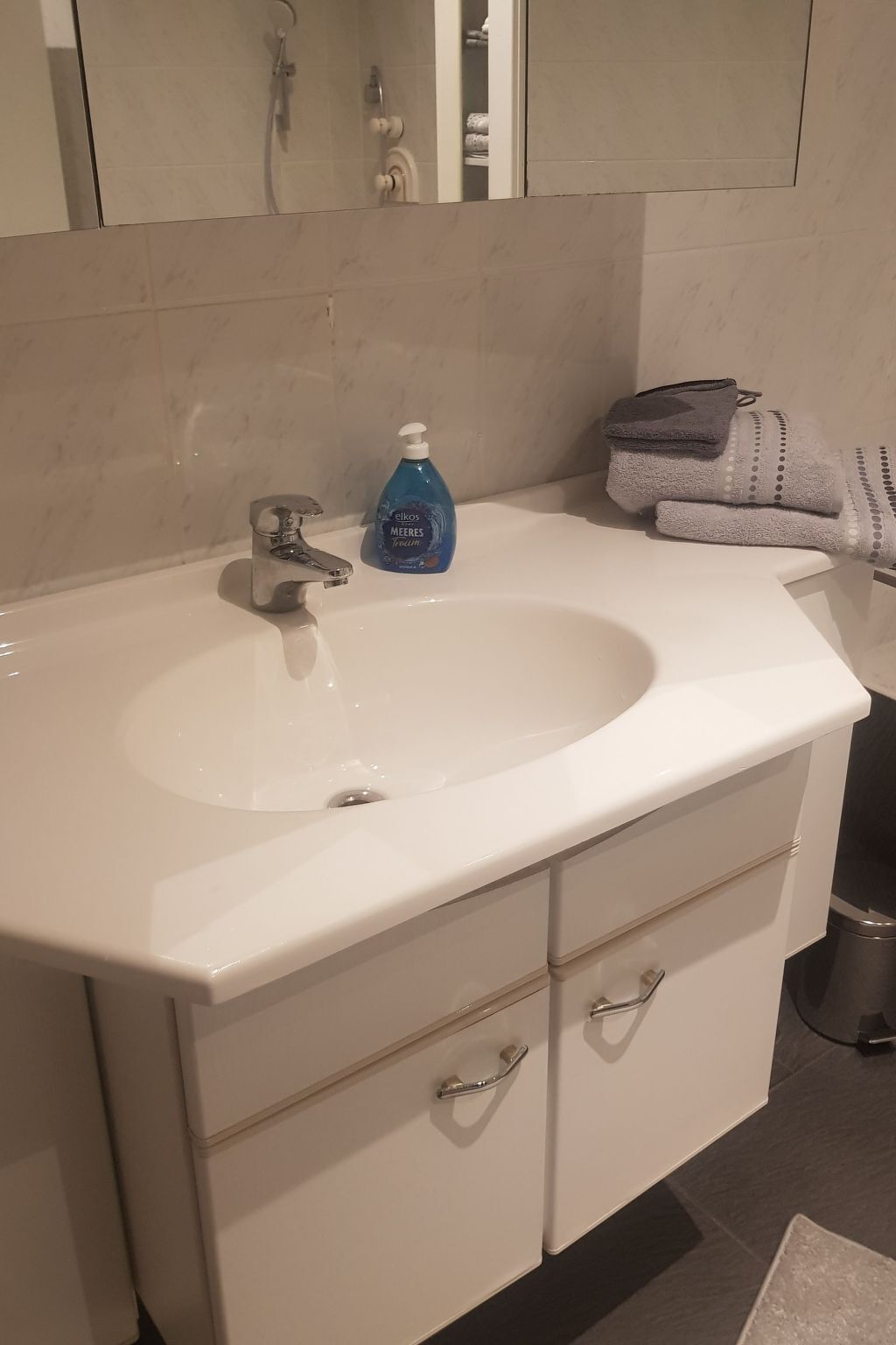 A bathroom with a white sink, a mirror, and a towel rack.