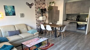 A modern living room with a sofa, coffee table, and a dining area with chairs. - Feriendomizil Adler by Interhome (Goslar)