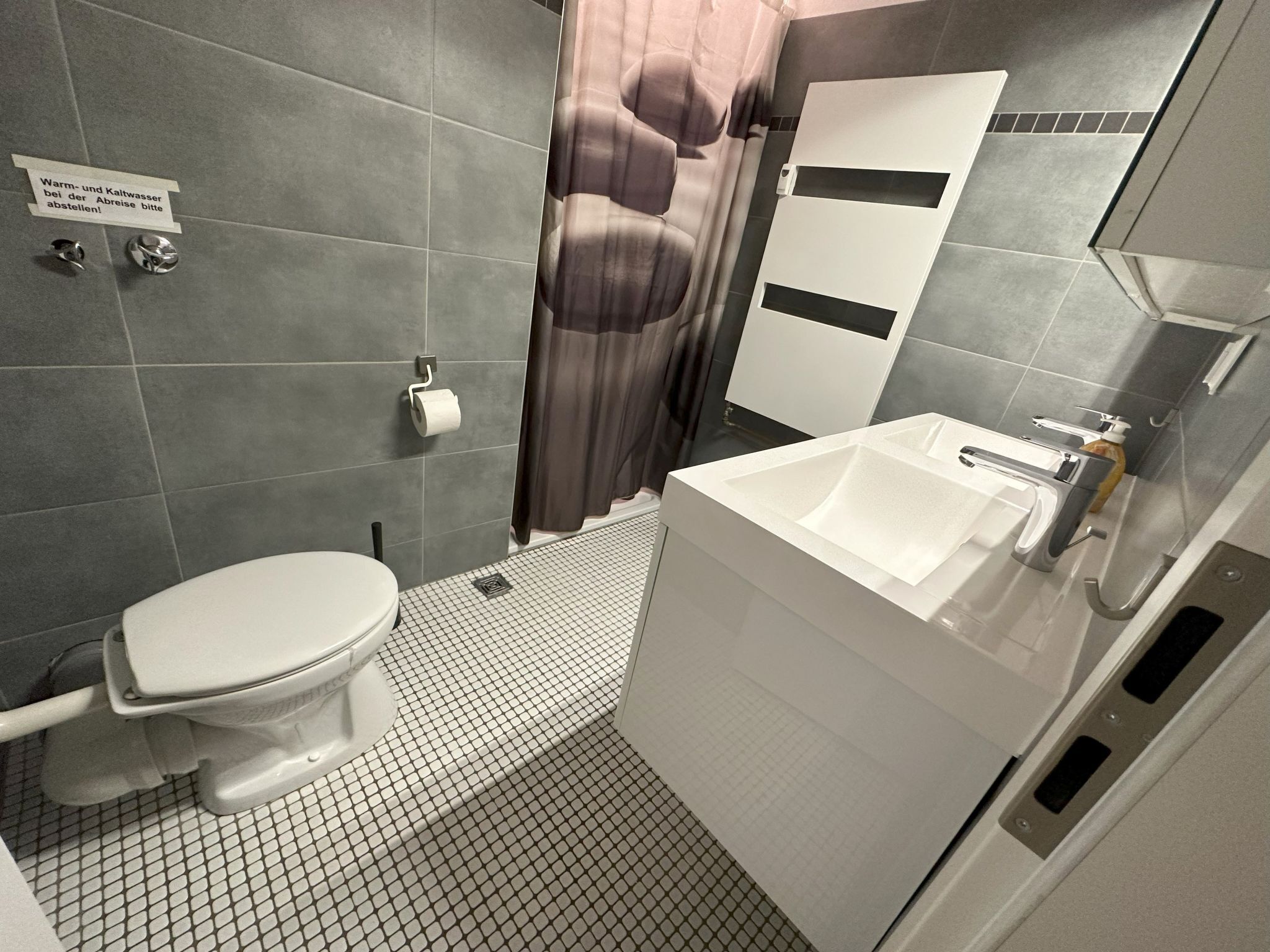 A bathroom with a toilet, sink, and shower curtain.