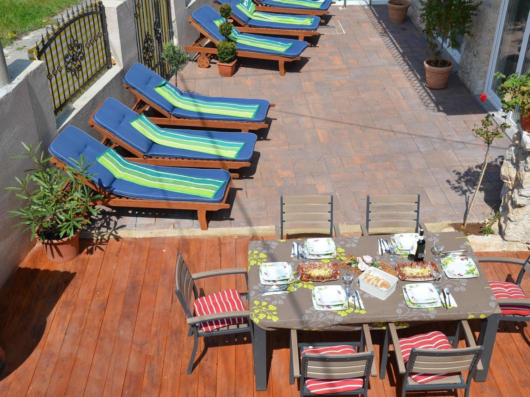 Une terrasse avec des chaises longues et une table à manger dressée pour le repas.