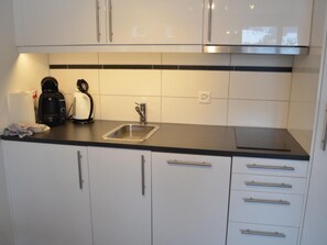 Een koelkast, een oven, een vaatwasser, kookgerei, borden en bestek