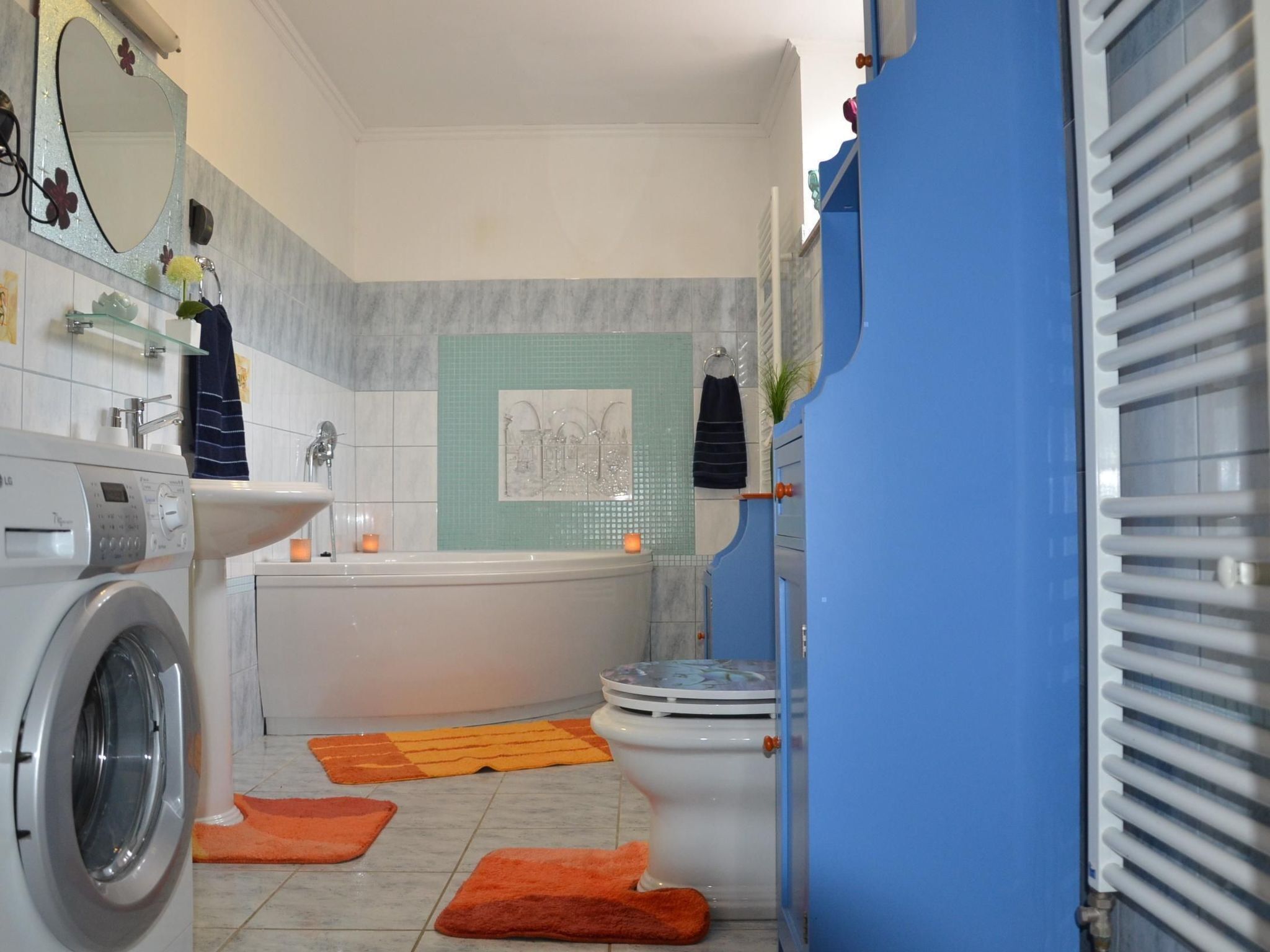 Een moderne badkamer met een wasmachine, wastafel, bad en toilet.